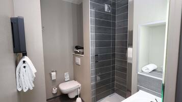A modern bathroom with a glass shower enclosure, a toilet, a sink, and a towel rack.