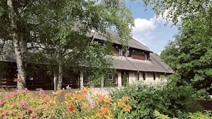 A two-story building with a sloped roof, surrounded by lush greenery and flowering plants. - ibis Egletons (Egletons)