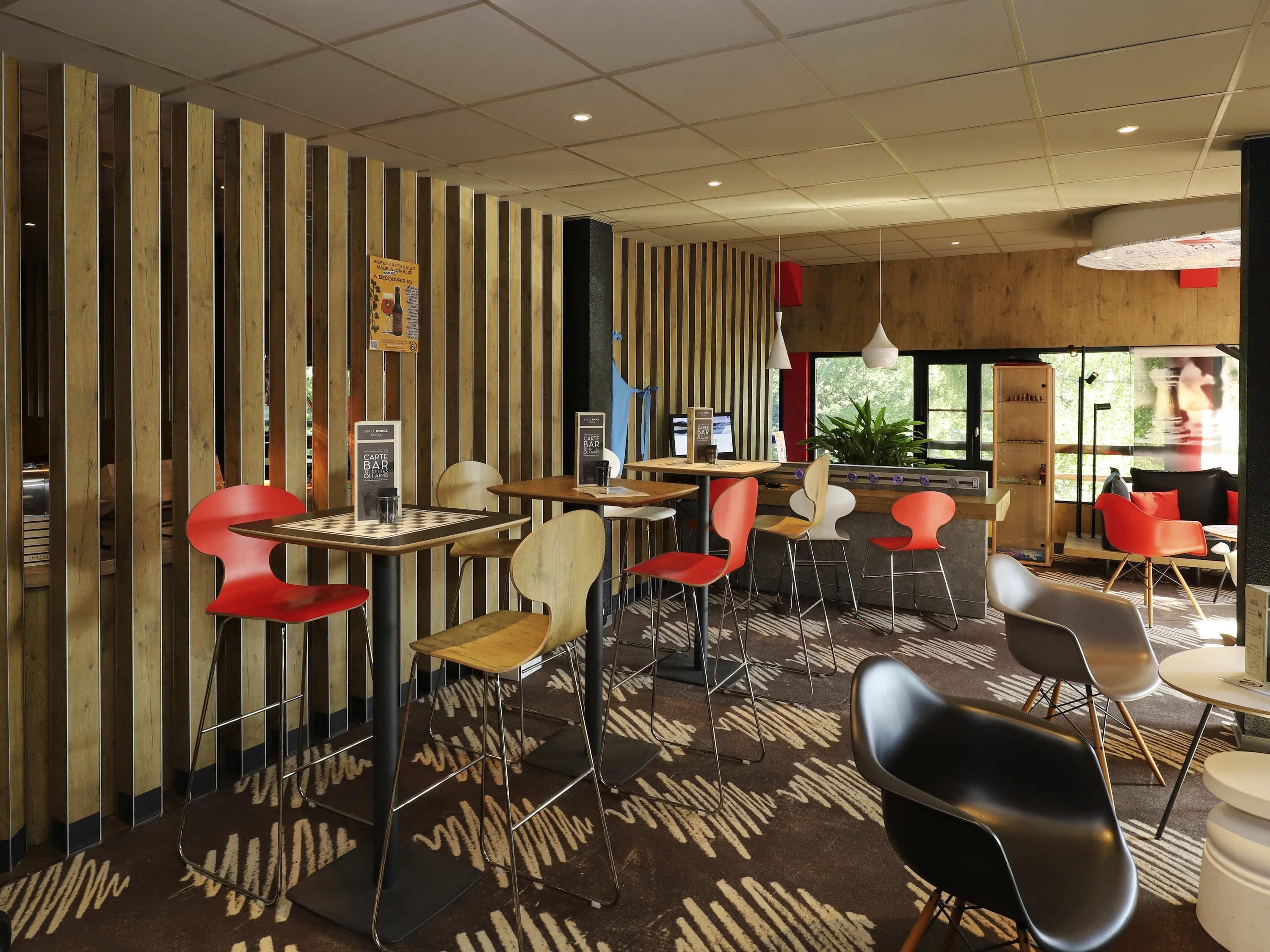 A modern cafe with wooden slat walls, multiple seating areas, and a patterned carpet.