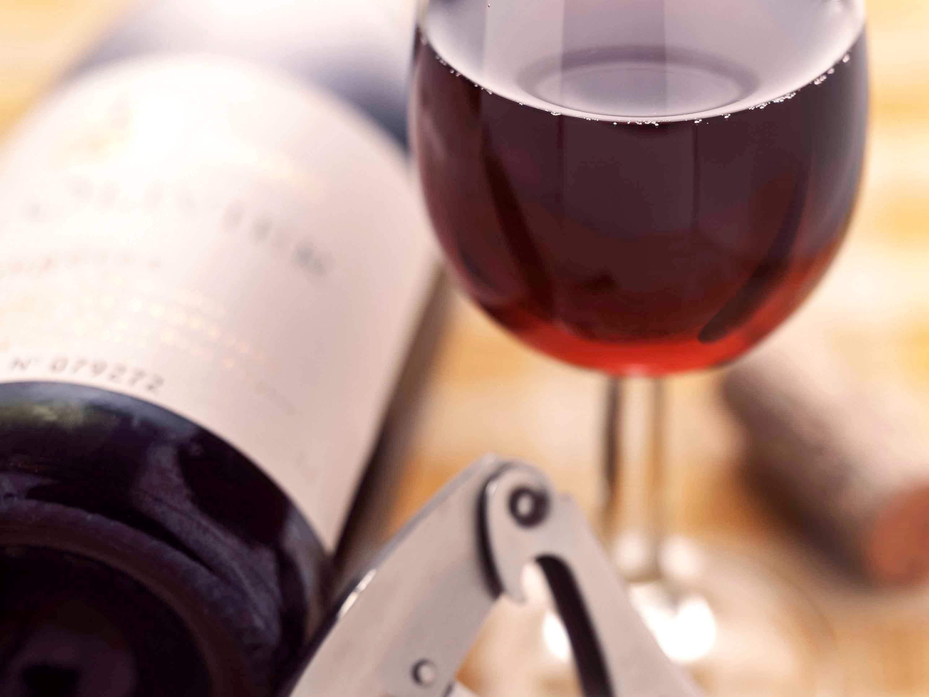 Una botella de vino y una copa de vino tinto.