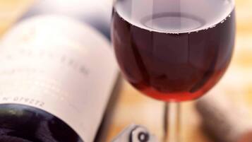 Una botella de vino y una copa de vino tinto.