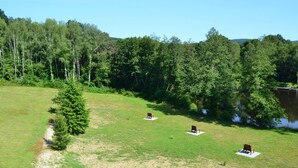 Eine Wiese mit drei hölzernen Bänken und einem kleinen Baum.