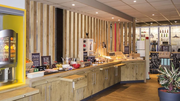 A modern bar area with wooden accents, a counter with various items, and a display of bottles. - ibis Egletons (Egletons)