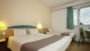 Quarto de hotel com duas camas, uma mesa e uma cadeira.