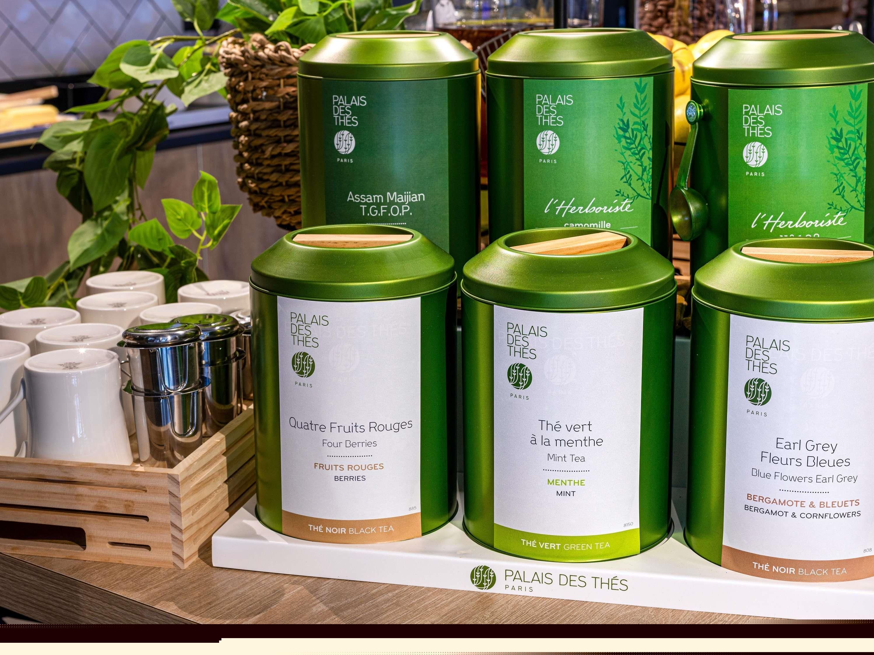 A display of green tea tins with labels indicating different flavors and types.