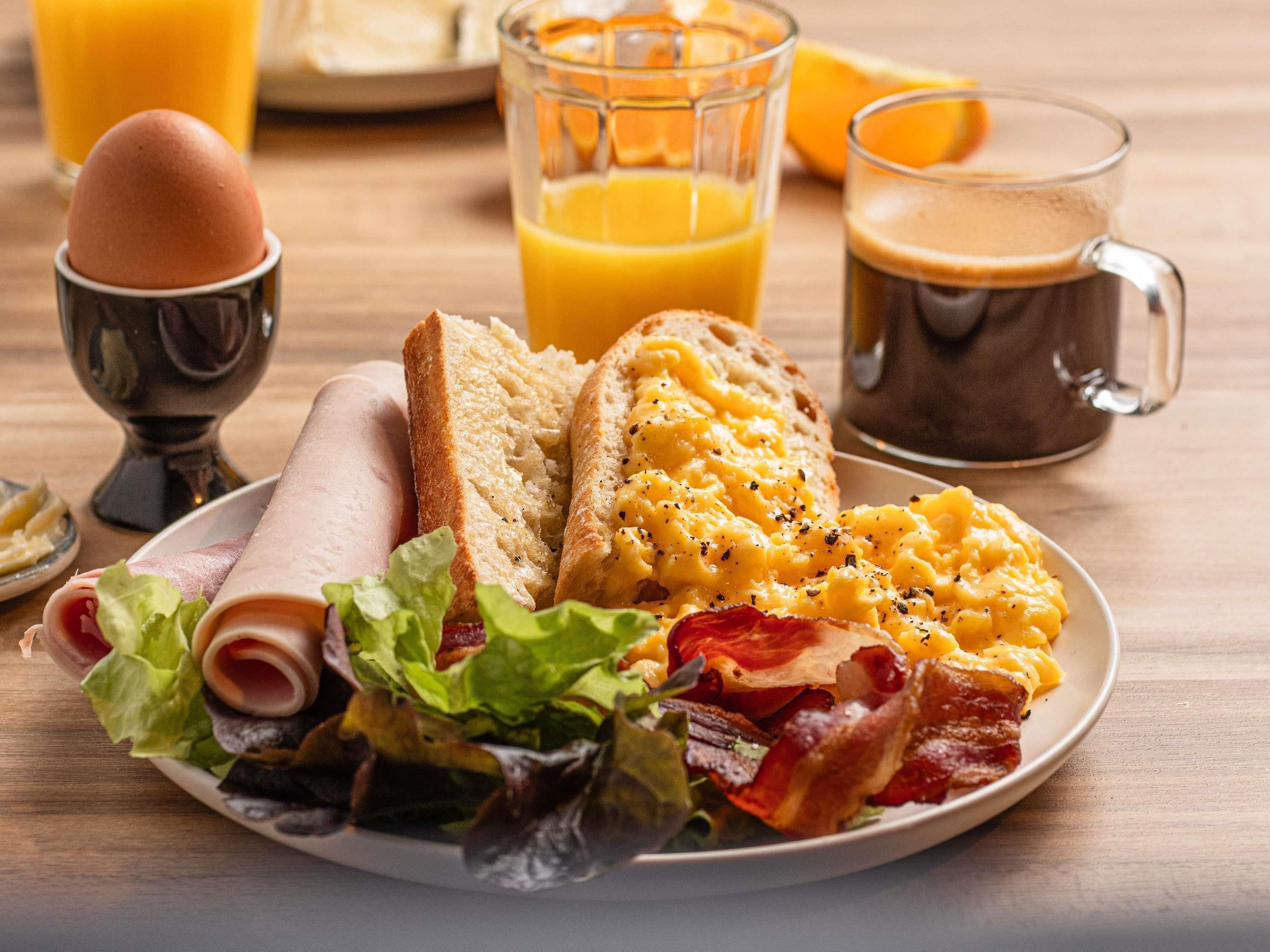 Un plato de desayuno con huevos, tocino, tostadas y un vaso de jugo de naranja.