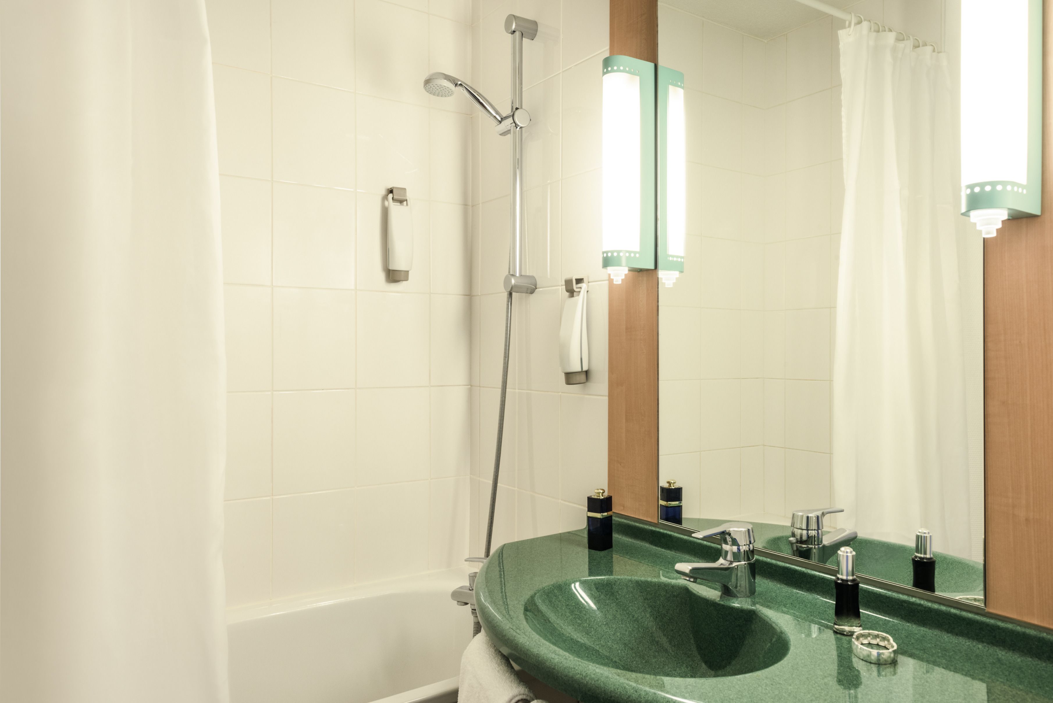 Un baño con lavamanos verde, bañera, ducha y espejo con iluminación.