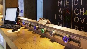A reception desk with a laptop, a signboard, and a wall with the text "MEDIA MARCHINER". - ibis Egletons (Egletons)