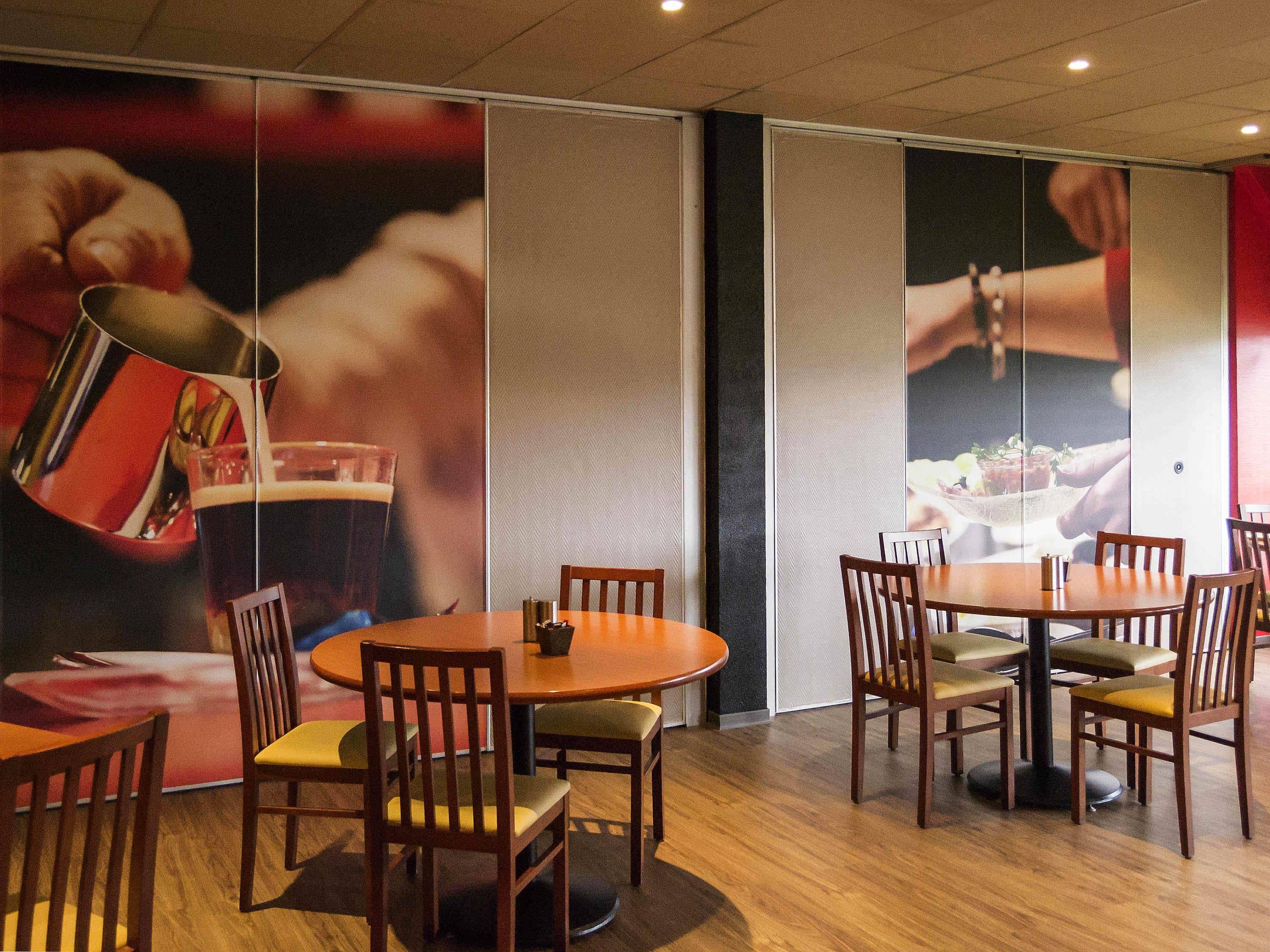 Un restaurante con mesas y sillas de madera, un cartel grande en la pared y un diseño de interiores moderno.
