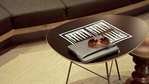 A round table with a black top and gold legs, a grey wallet, and a pair of sunglasses on top. - ibis Egletons (Egletons)
