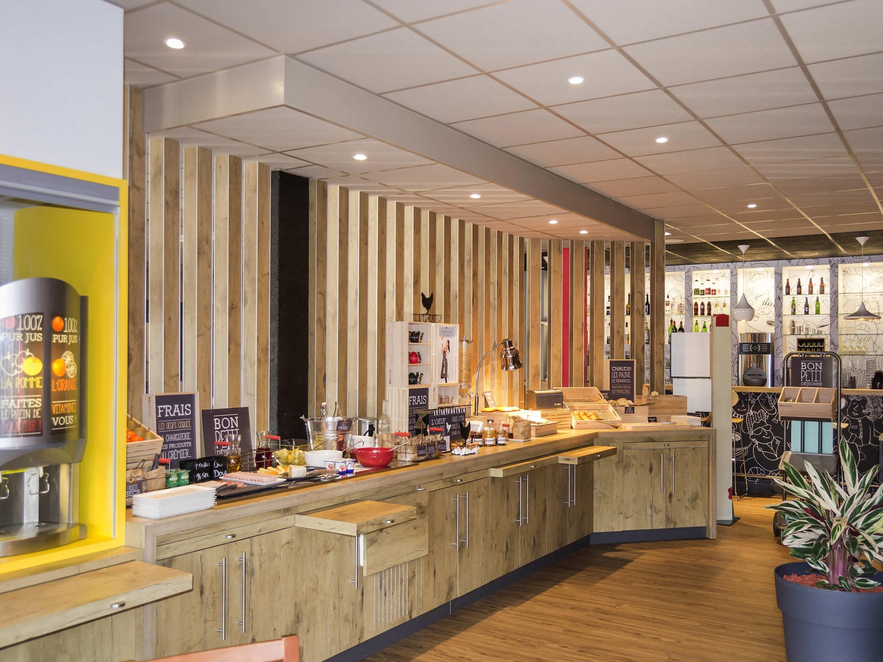 A modern bar area with wooden accents, a counter with various items, and a display of bottles.