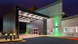 A modern building with a prominent entrance, a covered walkway, and a well-lit facade. - Wyndham Garden Ankeny/Des Moines (Ankeny)
