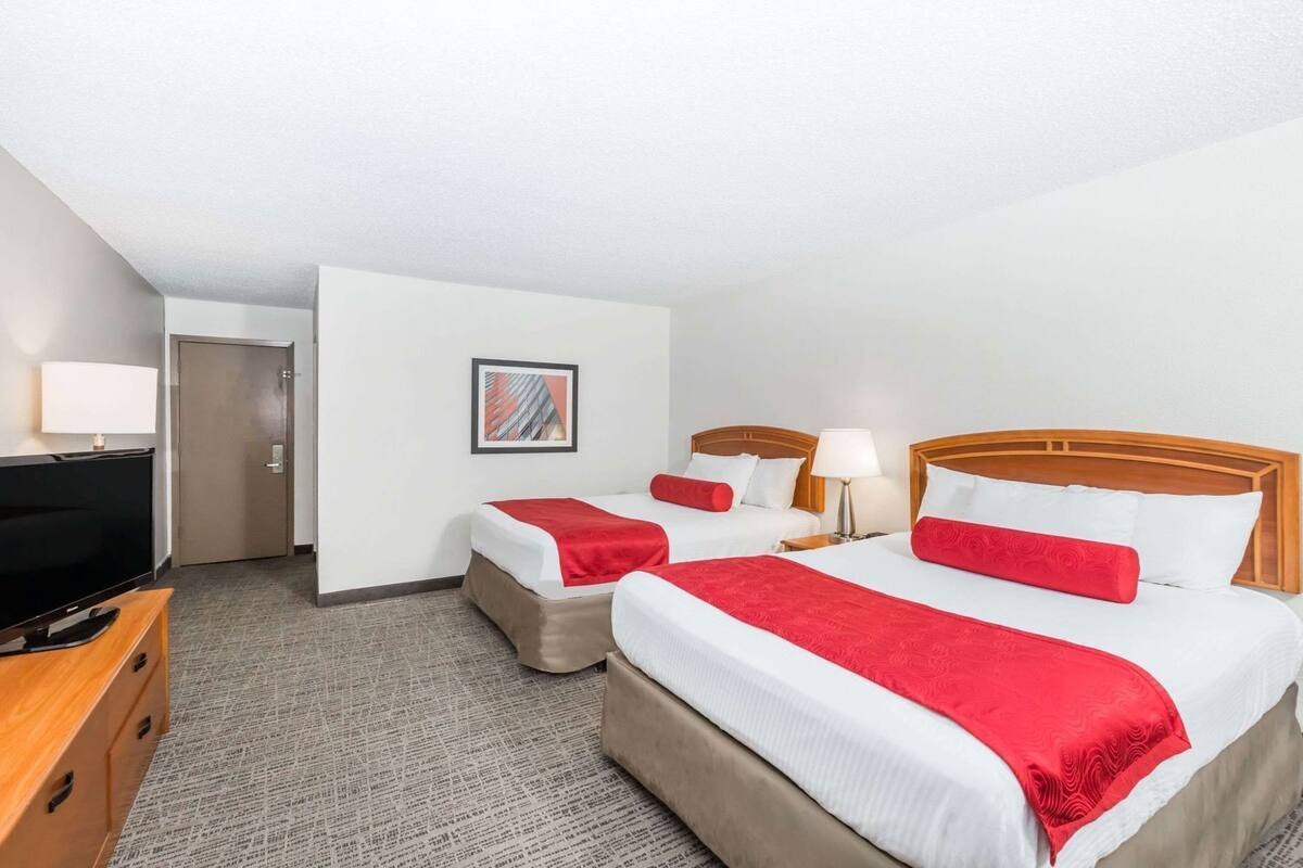Habitación de hotel con dos camas, televisión, escritorio y puerta.