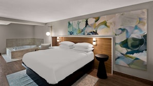 A modern hotel room with a large bed, a separate bathroom, and abstract wall art. - Wyndham Garden Ankeny/Des Moines (Ankeny)