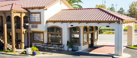 A two-story building with a red-tiled roof, large windows, and a covered patio area.