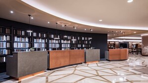 Eine moderne Lobby mit einer gebogenen Rezeption, einem großen Bücherregal und einem geometrisch gemusterten Boden.