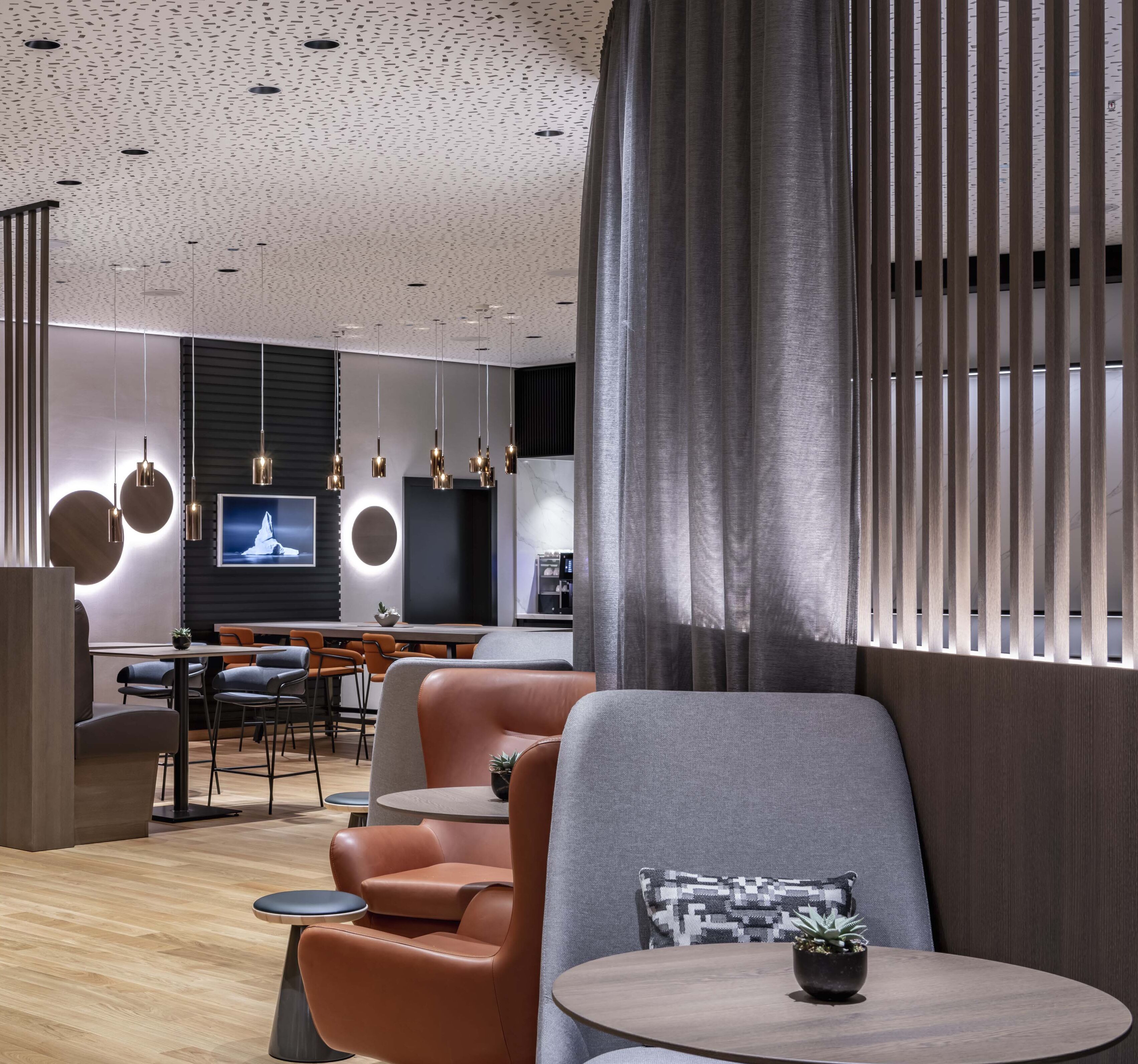 Un interno moderno con angolo salotto, un bar e uno schermo televisivo.
