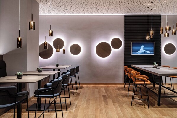 Una sala de conferencias moderna con apliques redondos en la pared, un televisor de pantalla plana y piso de madera.