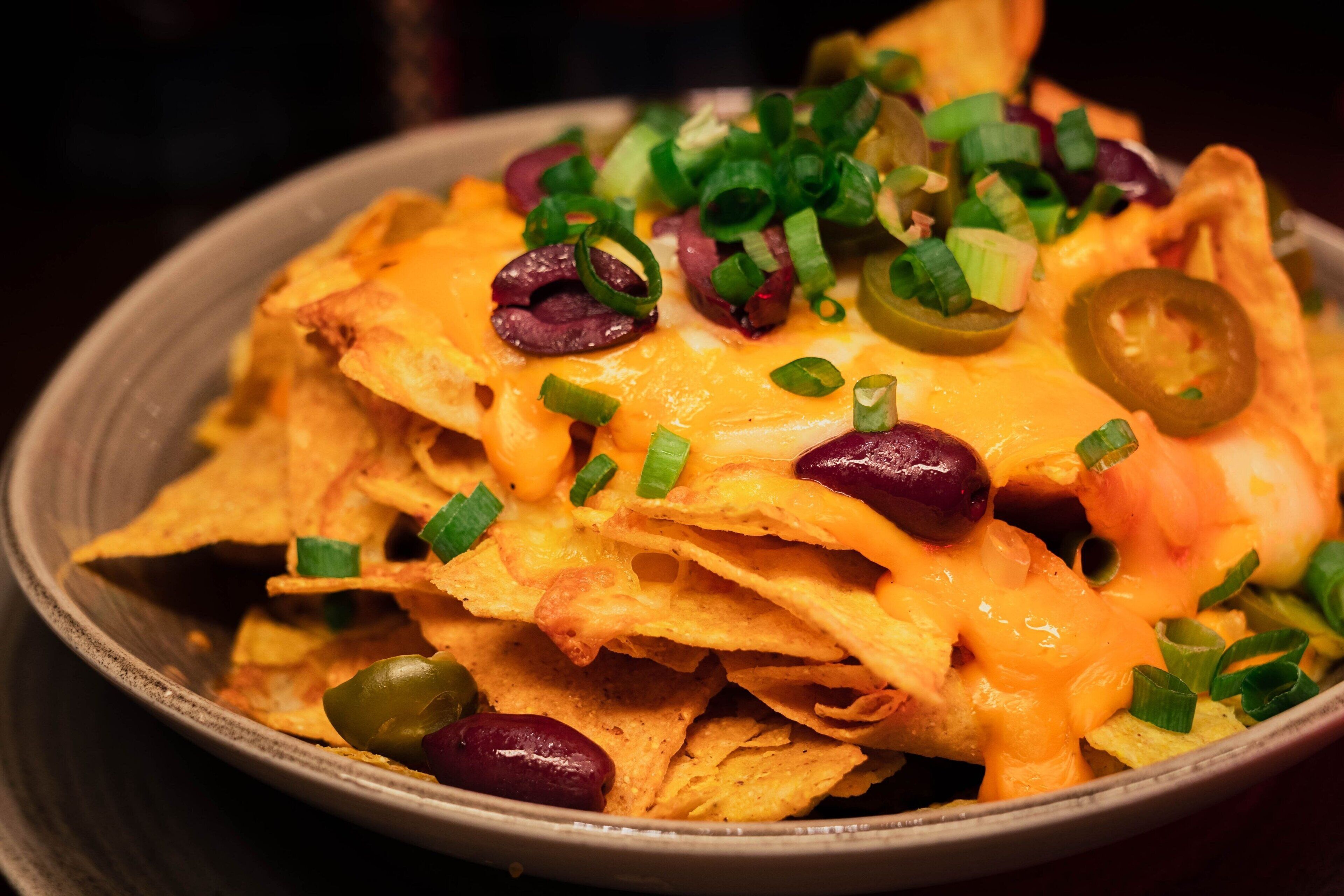 Nachos cubiertos de queso, jalapeños y cebollas verdes.