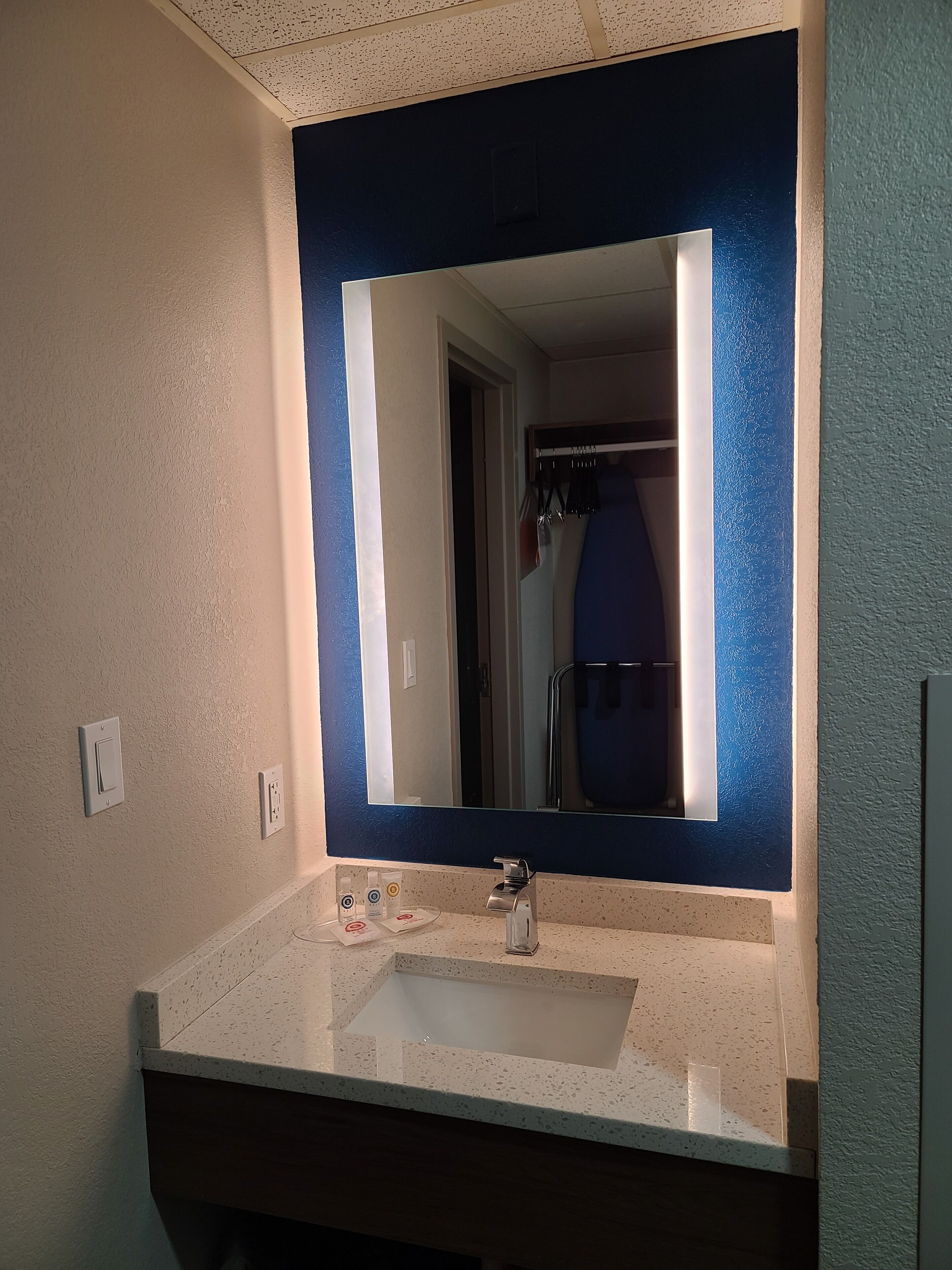 A bathroom with a white sink, a mirror with a blue frame, and a towel rack.