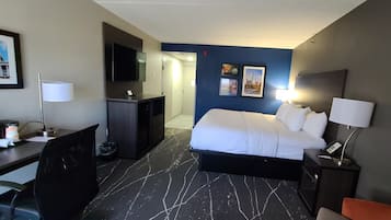 Hotellihuone, jossa on sänky, työpöytä, tuoli ja televisio.