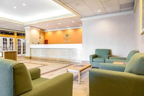 A hotel lobby with a reception desk, seating area, and a fire extinguisher.