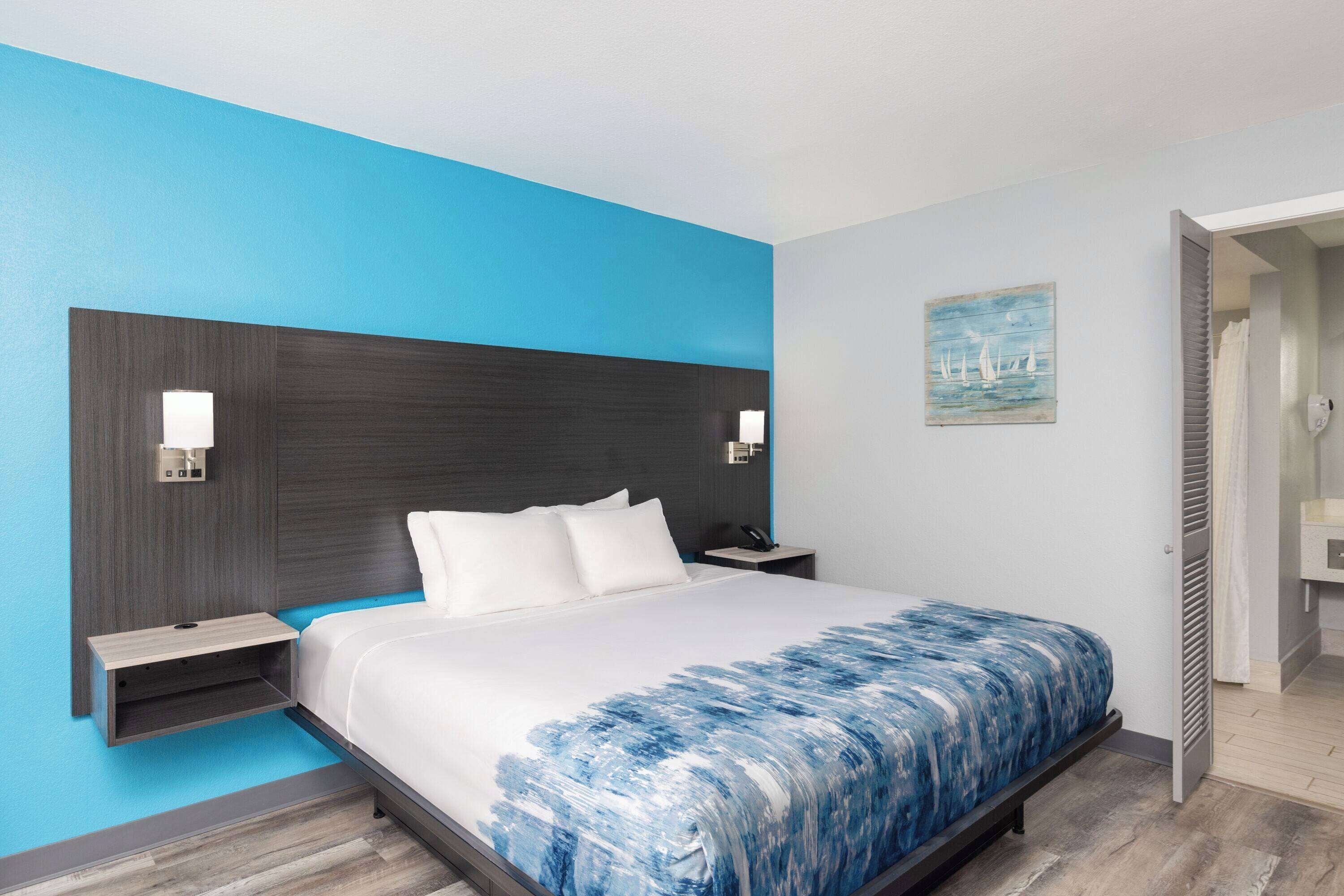 Habitación de hotel con cama, mesitas de noche y un cuadro en la pared.