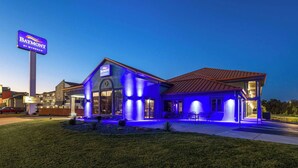 Un hotel con un cartel llamativo, una entrada bien iluminada y un área de estar exterior visible.