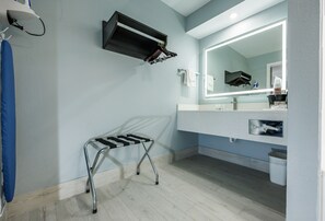 Une salle de bain avec un plancher en bois, un banc blanc, un miroir et un porte-serviettes.