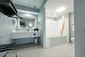 Une salle de bain moderne avec un grand miroir, une baignoire et des toilettes.