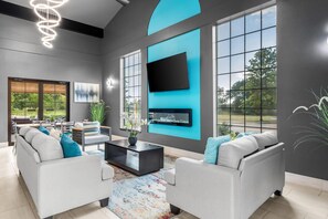 A modern living room with a large TV, grey sofas, and a coffee table. - Baymont by Wyndham Branson Thousand Hills (Branson)