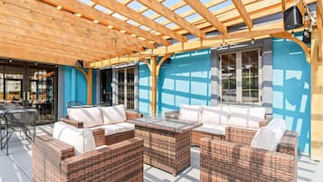 Un espacio de estar al aire libre con mobiliario de mimbre y una pérgola de madera.