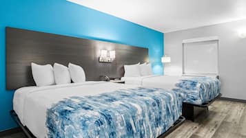 Una habitación de hotel con una cama grande, una mesita de noche, una lámpara de pared y una ventana.