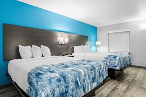 A hotel room with a large bed, a bedside table, a nightstand, a wall-mounted light, and a window. - Baymont by Wyndham Branson Thousand Hills (Branson)