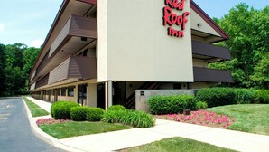 Un Red Roof Inn con una estructura de dos pisos, estacionamiento y jardines bien cuidados.