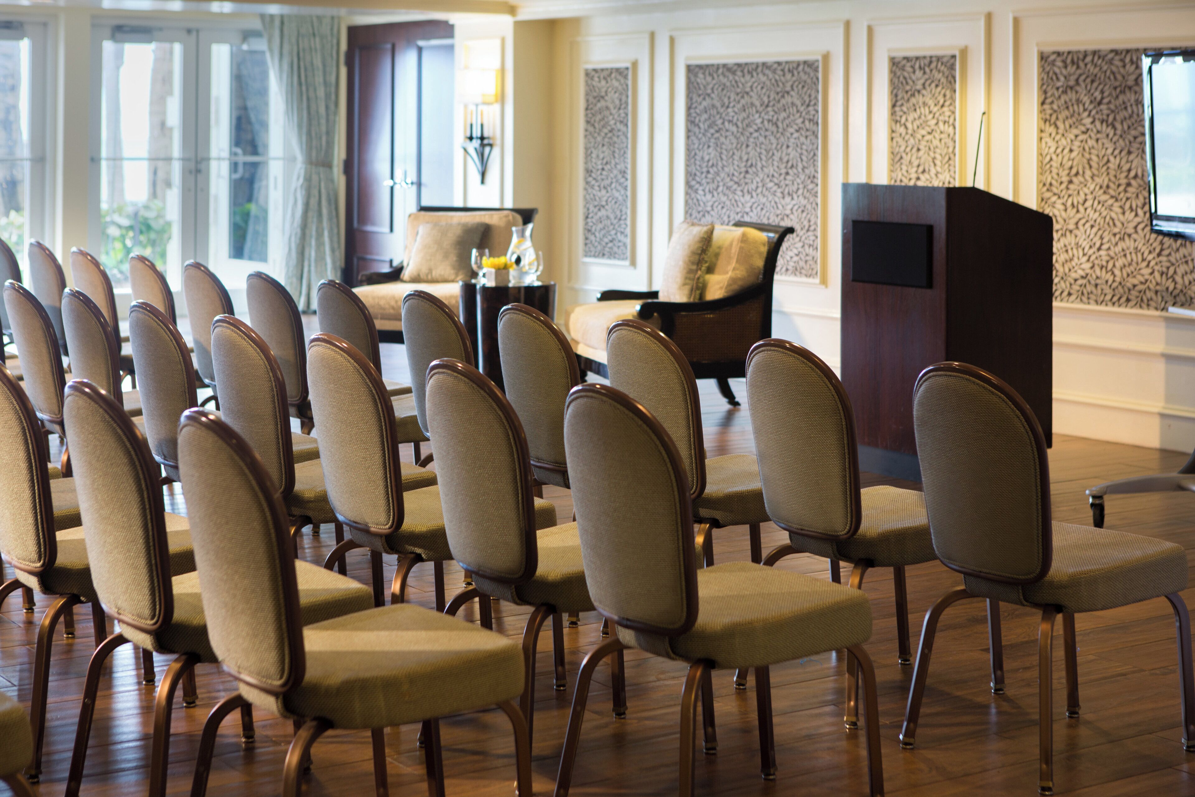 A hotel lobby with rows of chairs, a sofa, a coffee table, and a decorative wall.
