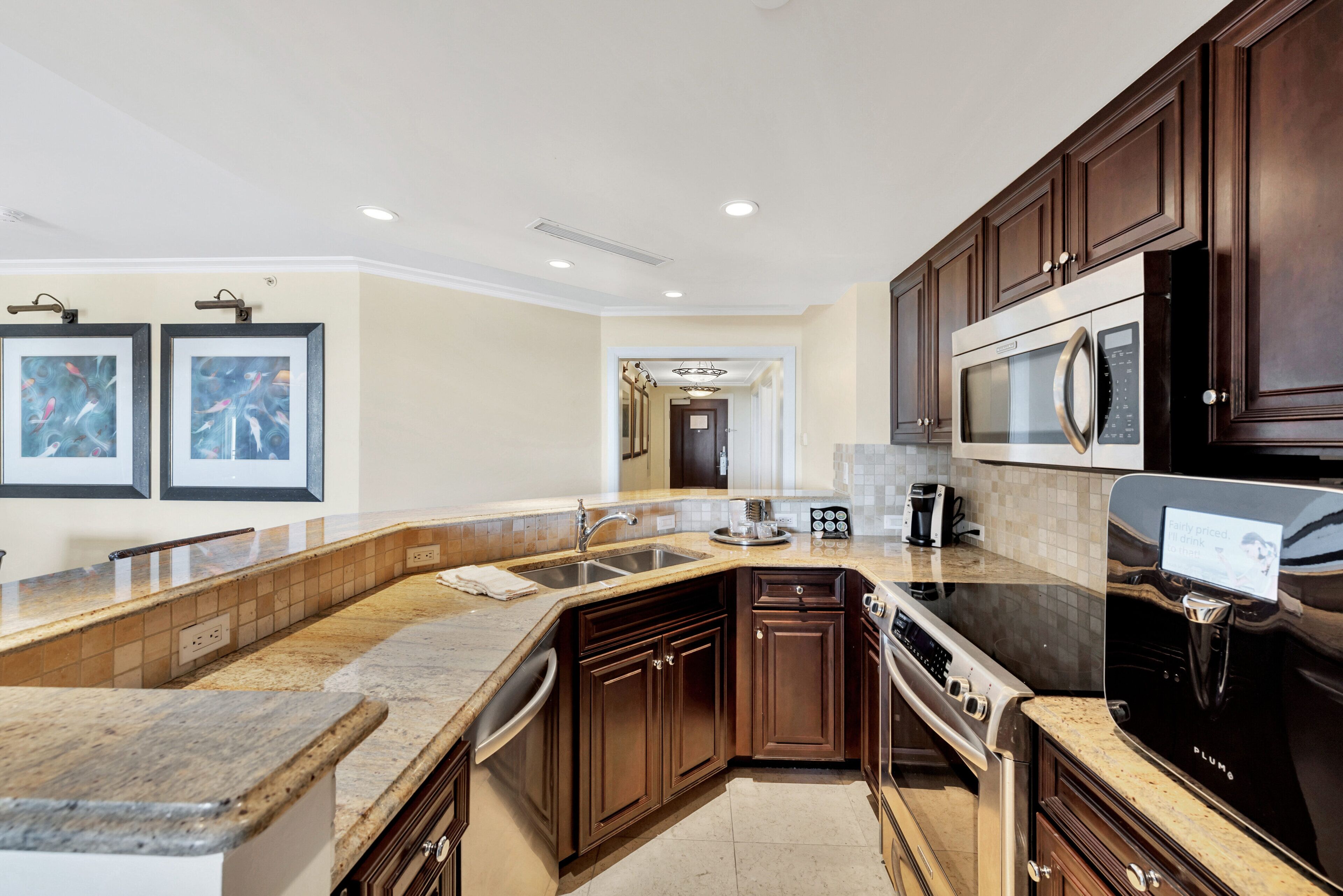A modern kitchen with dark wood cabinets, a stainless steel refrigerator, and a granite countertop.