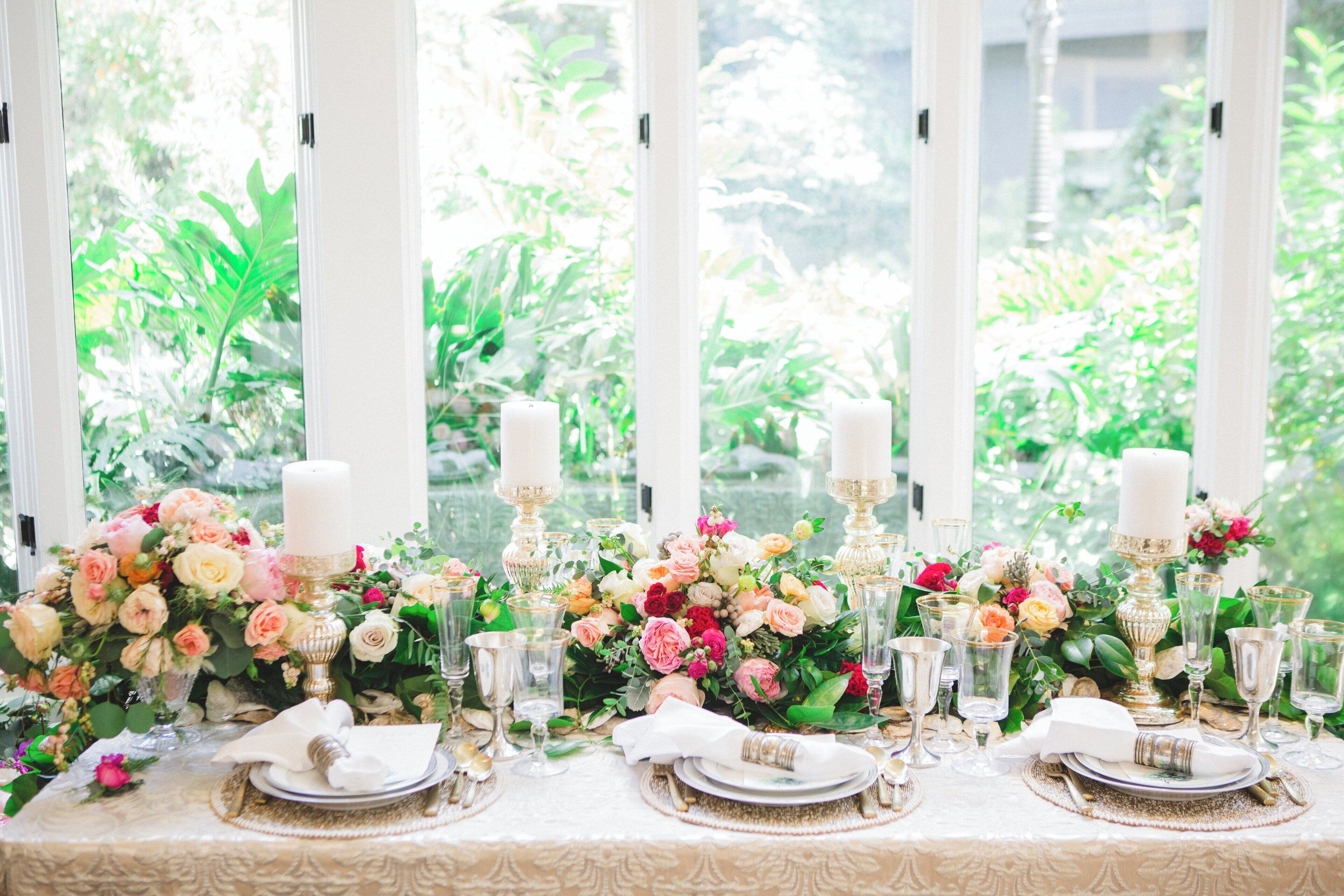 A table set for a formal event with floral centerpieces, candles, and glassware.