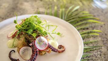 A plate of food with octopus, greens, and radishes.