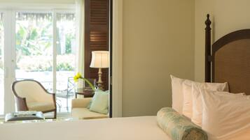 Quarto de hotel com cama, poltrona, luminária e vista para o exterior.