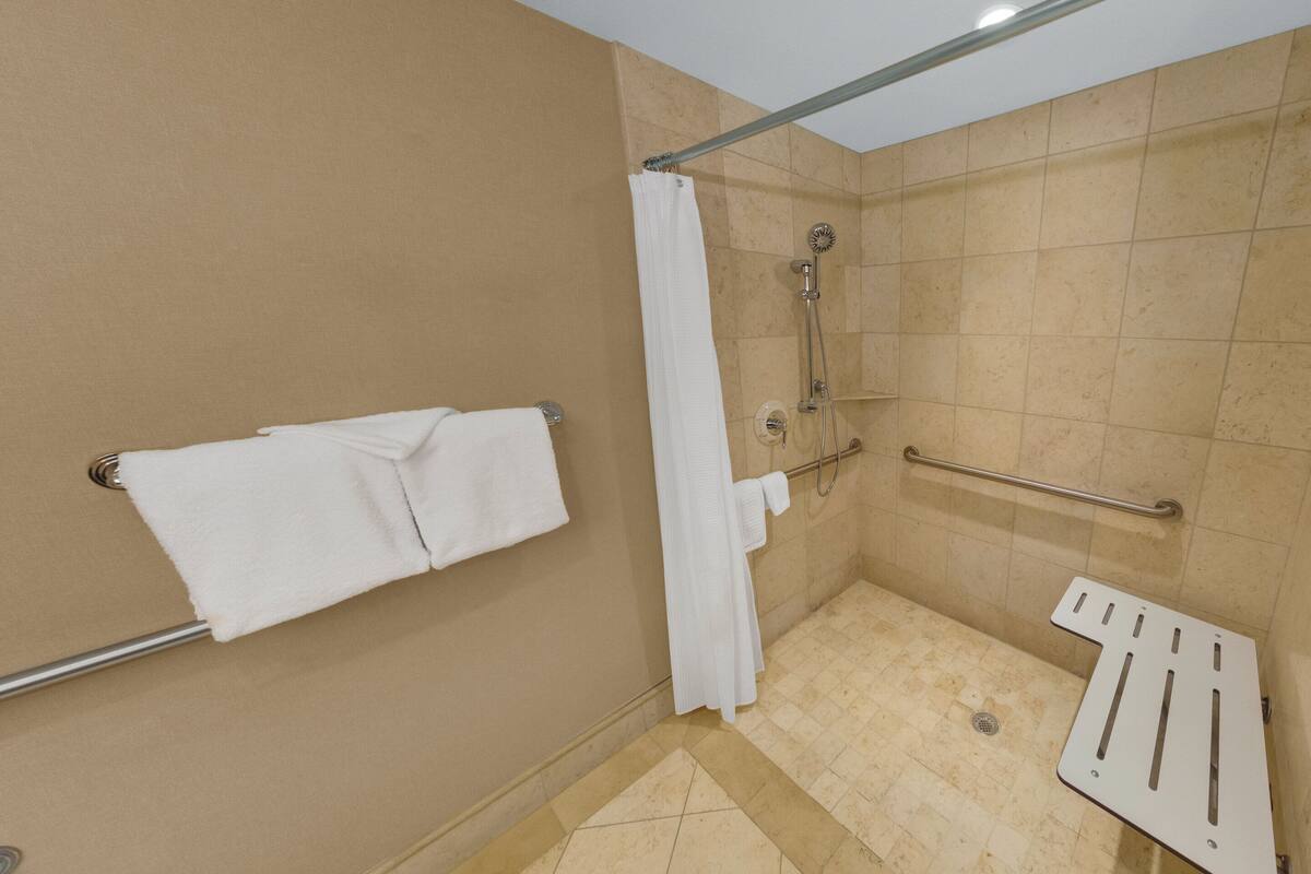 A shower area with a grab bar, a towel rack, and a showerhead.