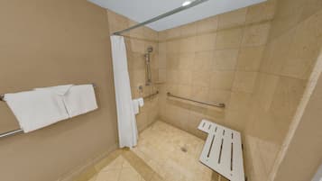 A shower area with a grab bar, a towel rack, and a showerhead.