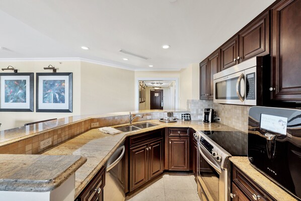 A modern kitchen with dark wood cabinets, stainless steel appliances, and a granite countertop.