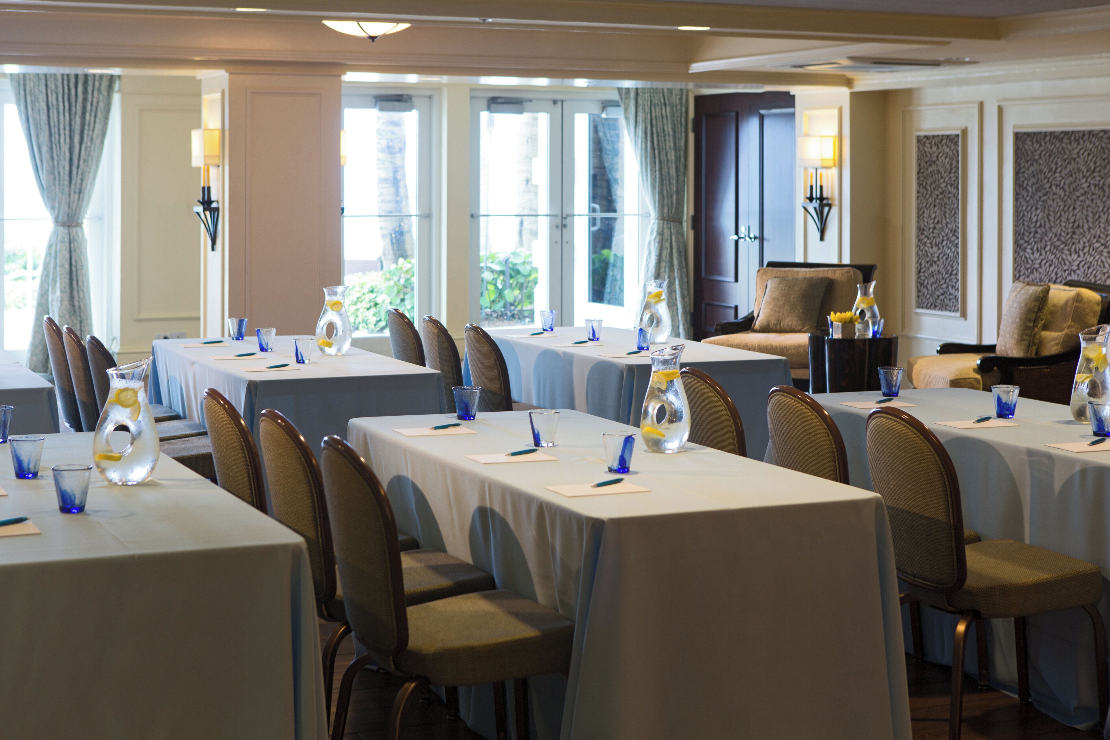 Une salle de conférence d’hôtel équipée de plusieurs tables, de chaises et agrémentée de vases décoratifs.
