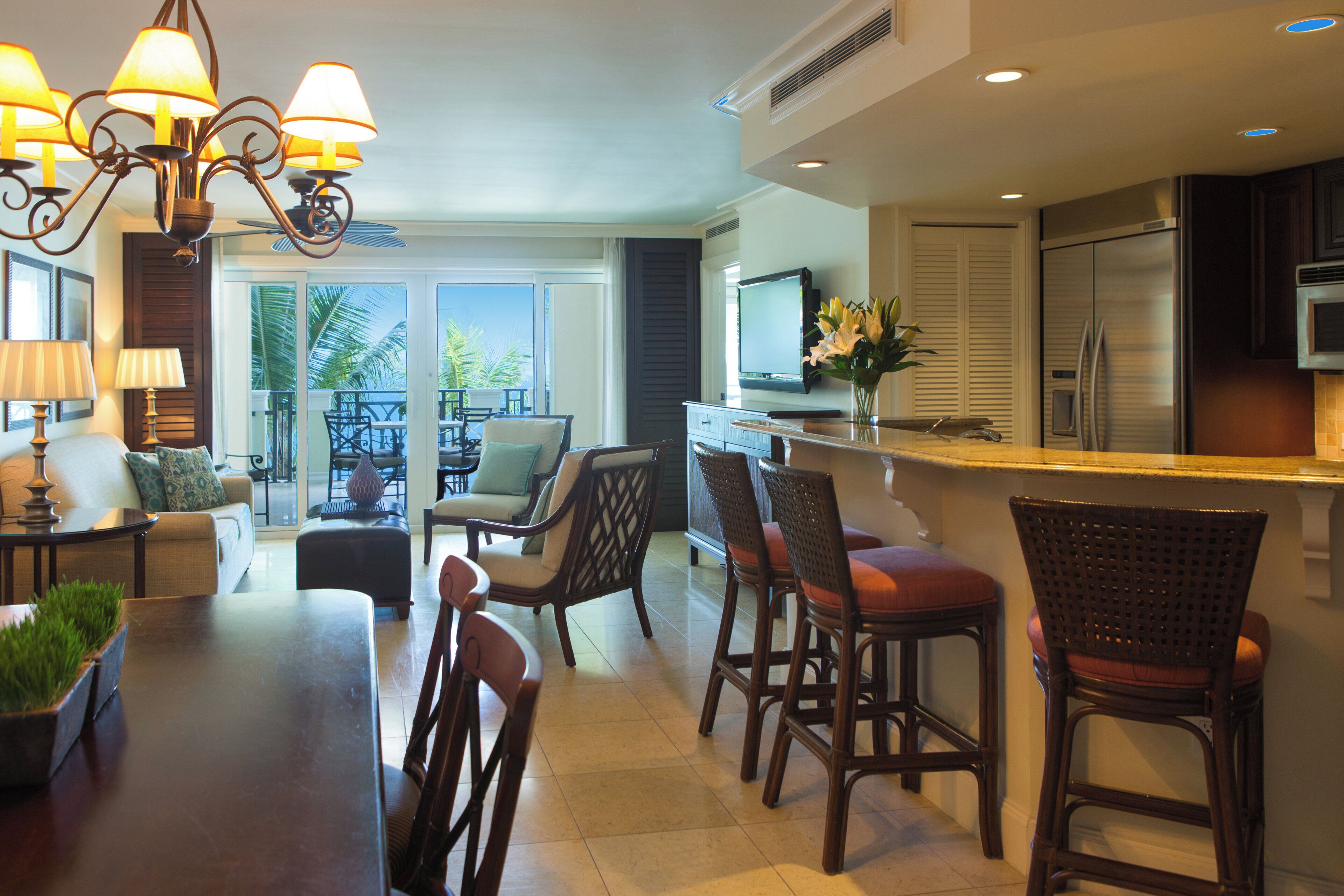 A spacious kitchen with a dining area, a TV, and a large window overlooking a balcony.
