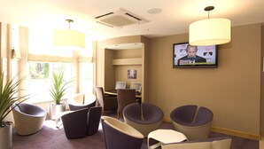 A hotel lobby with seating, a television, and a window. - Premier Inn London Kensington - Olympia (London)