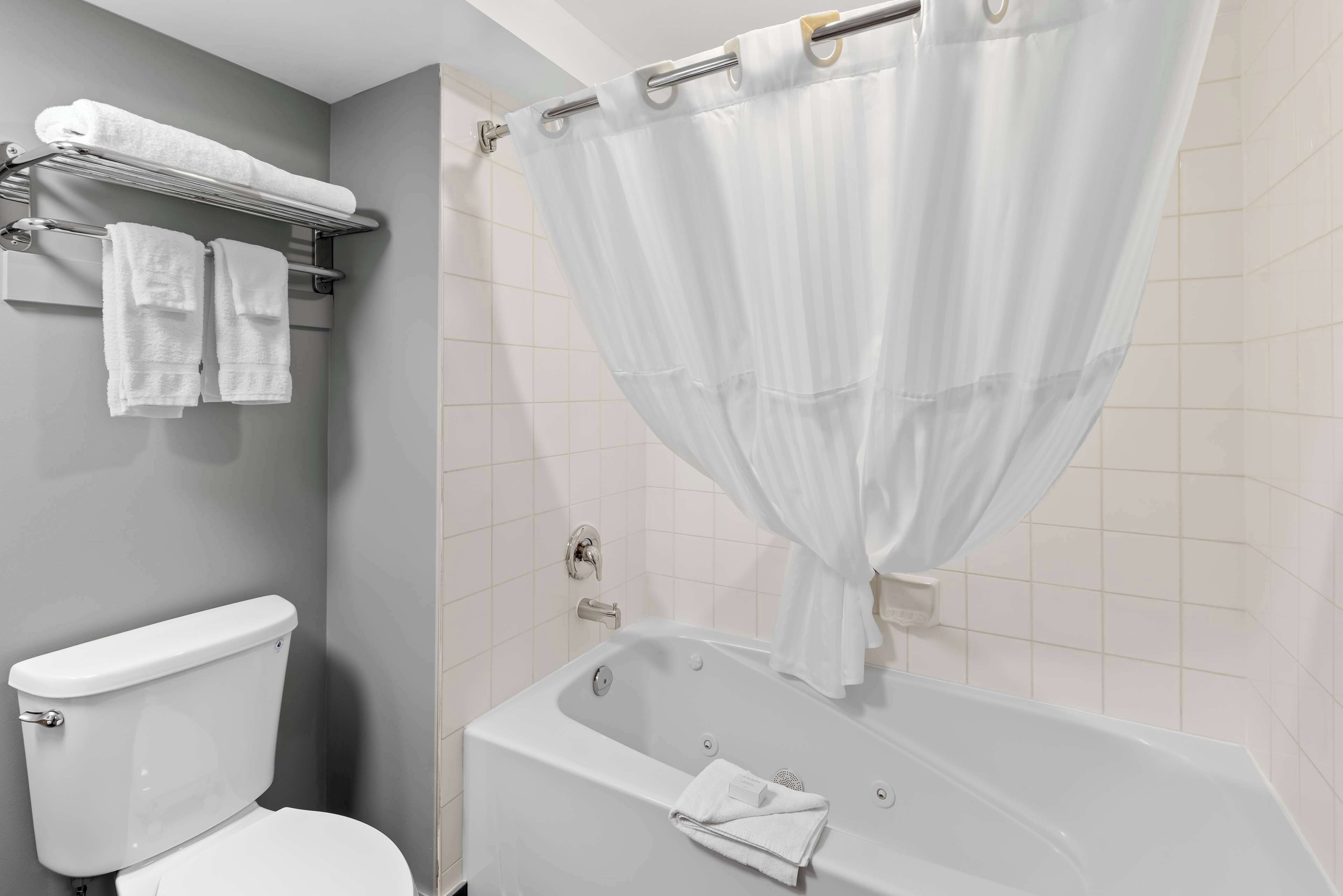 A bathroom with a bathtub, toilet, and towel rack.