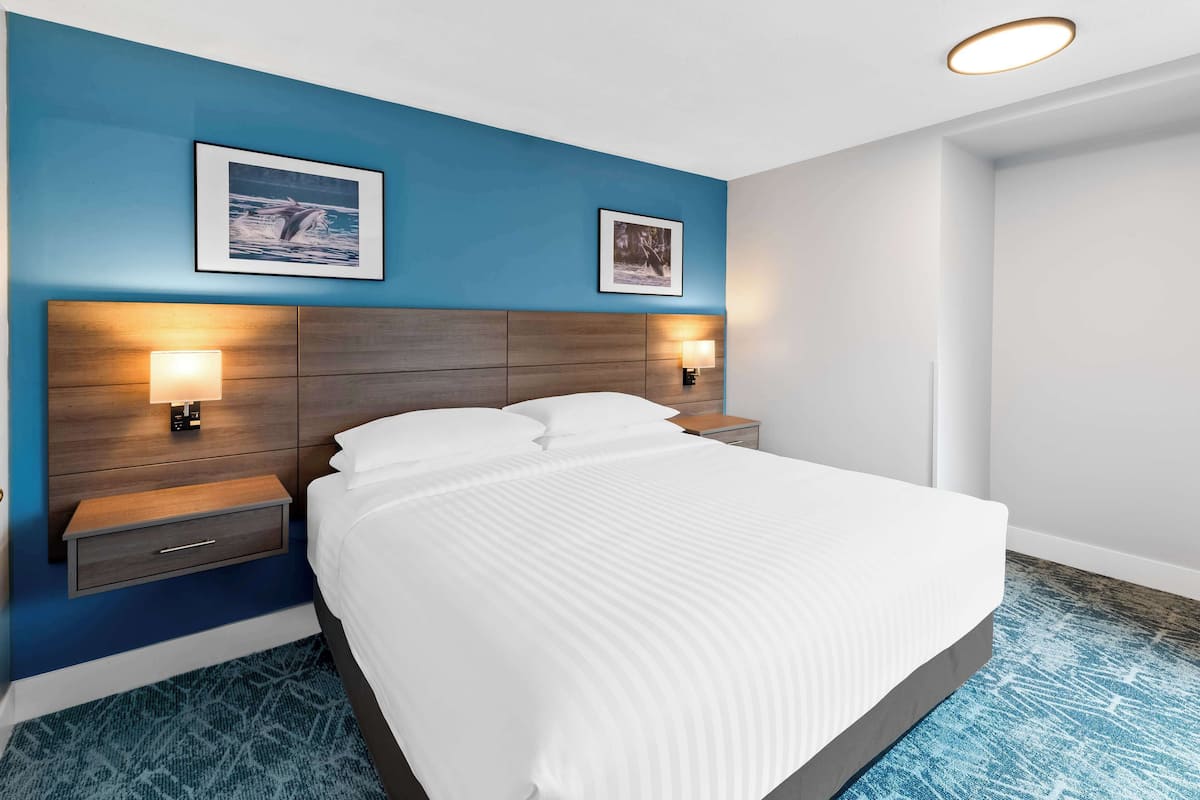 Ein Hotelzimmer mit einem großen Bett, zwei Nachttischen an der Wand und jeweils einer Wandlampe.