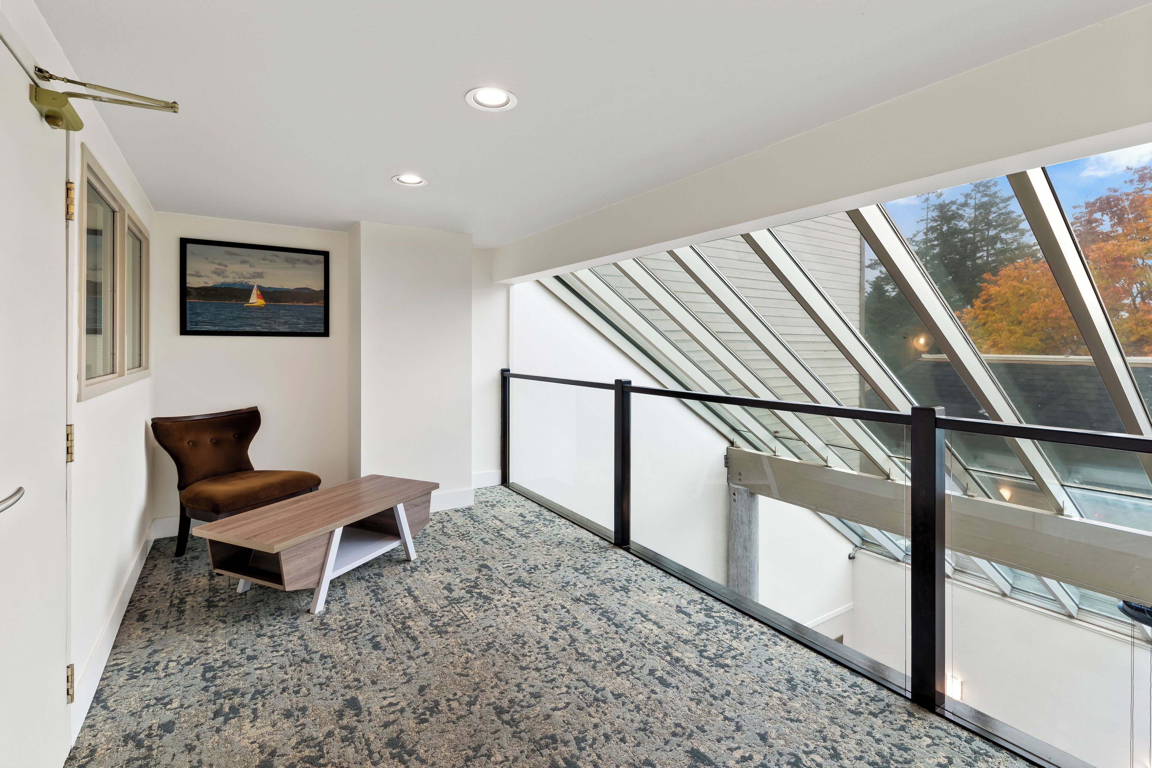 A modern room with a large skylight, a wooden bench, and a framed picture on the wall.