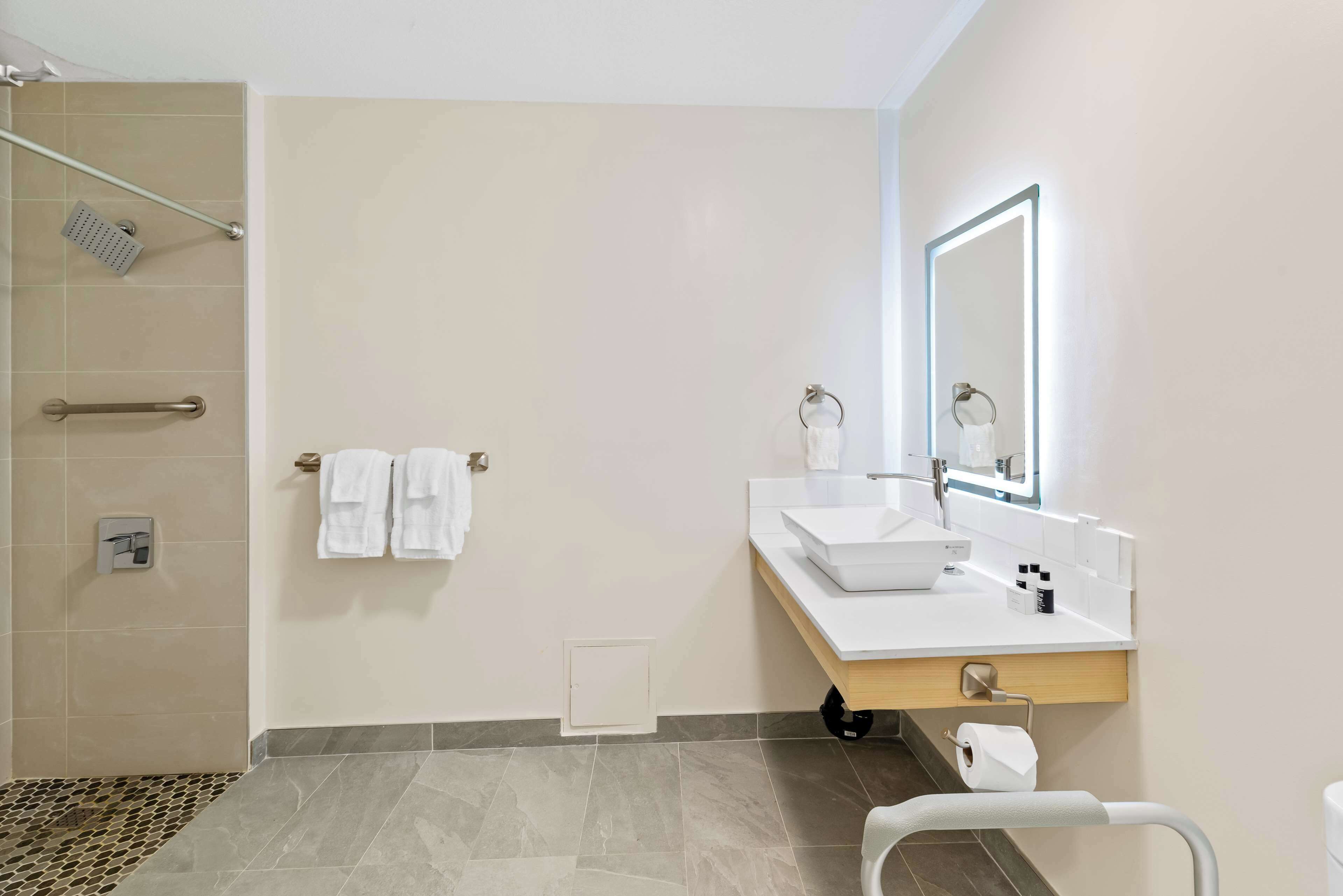 Un baño moderno con ducha, lavamanos y espejo.